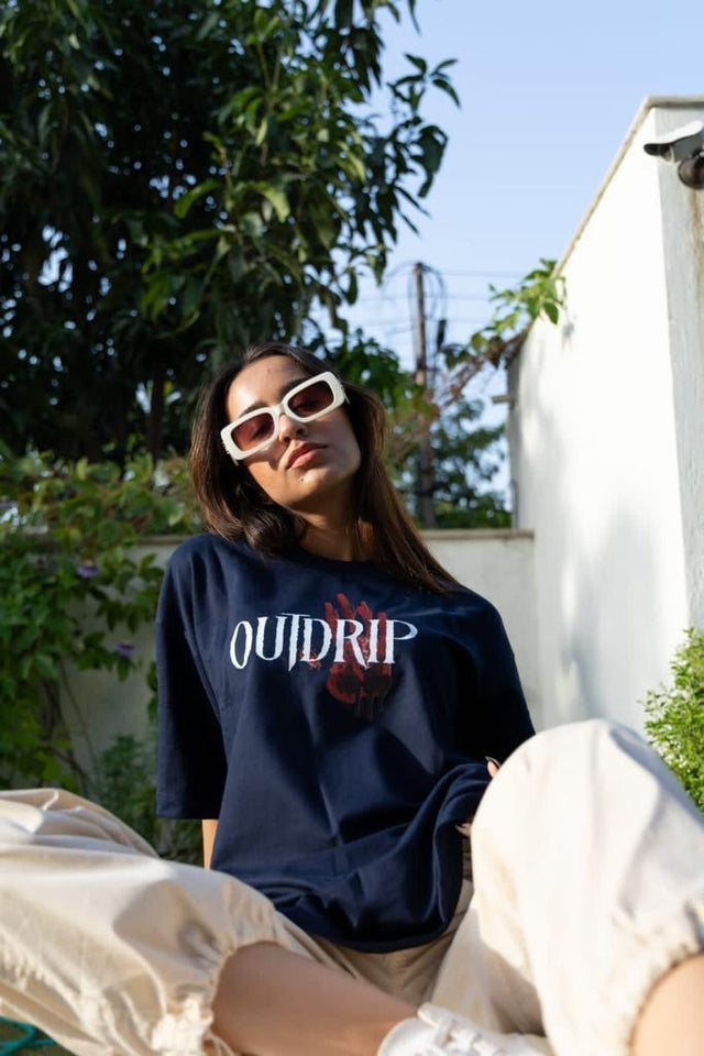 Female model in blue Skulls & Roses tee by Outdrip, styled with a relaxed streetwear aesthetic.