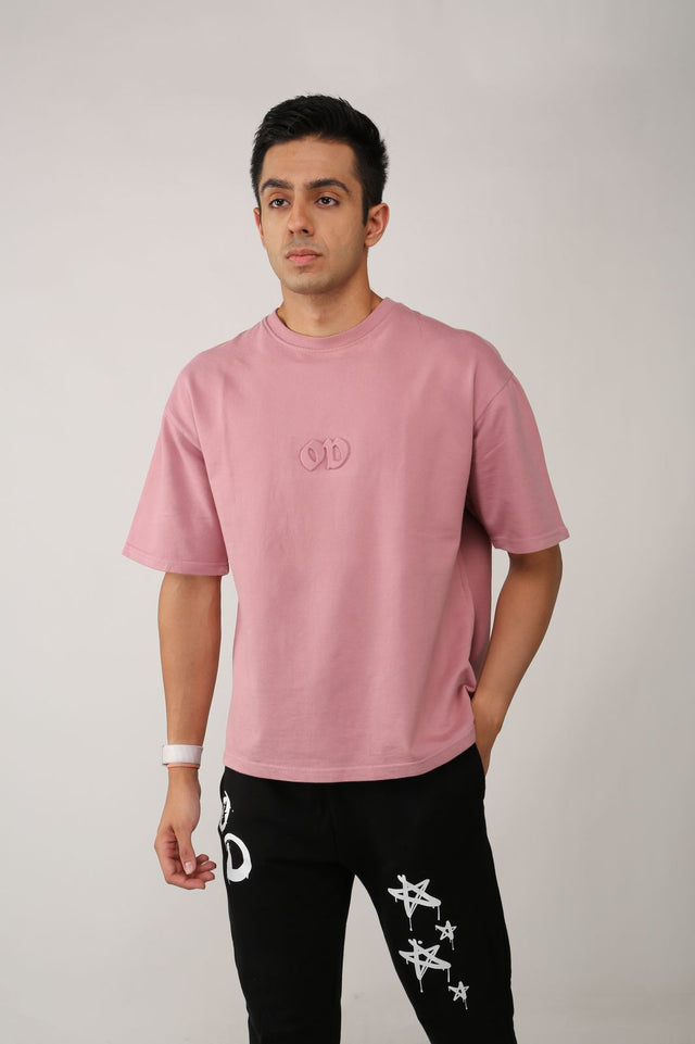 Male model wearing EMBOSSED LOGO T-shirt – pastel pink 240 GSM tee with subtle yet striking 3D embossed logo, styled with STAR bottoms